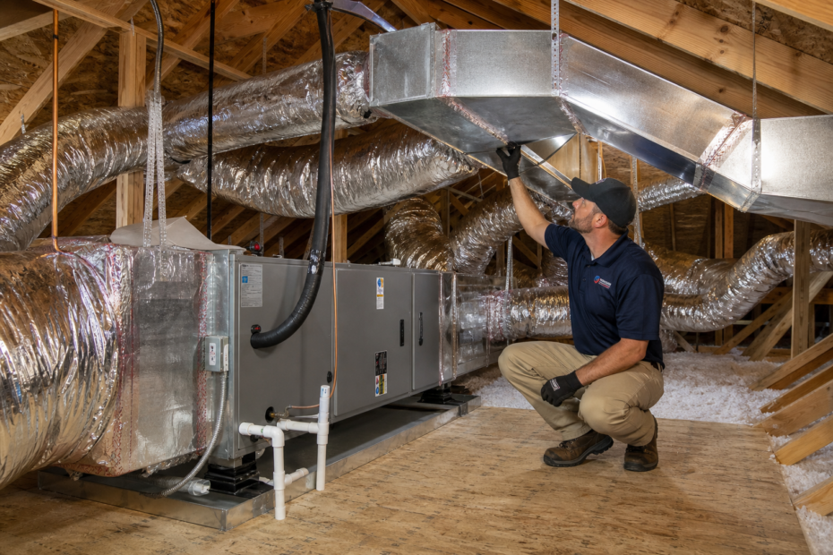 Technician inspecting existing HVAC ductwork during a home system replacement